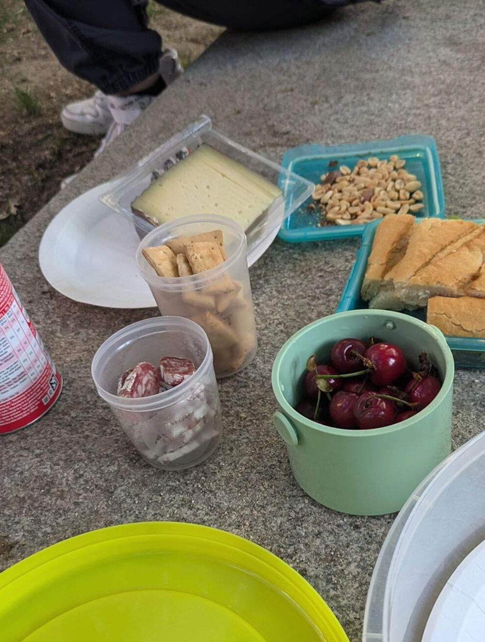 En la pared de un parque hay varios platos repartidos en latas de Tupperware: queso, cerezas, patatas fritas y bocadillos. Cerezas, patatas fritas y bocadillos